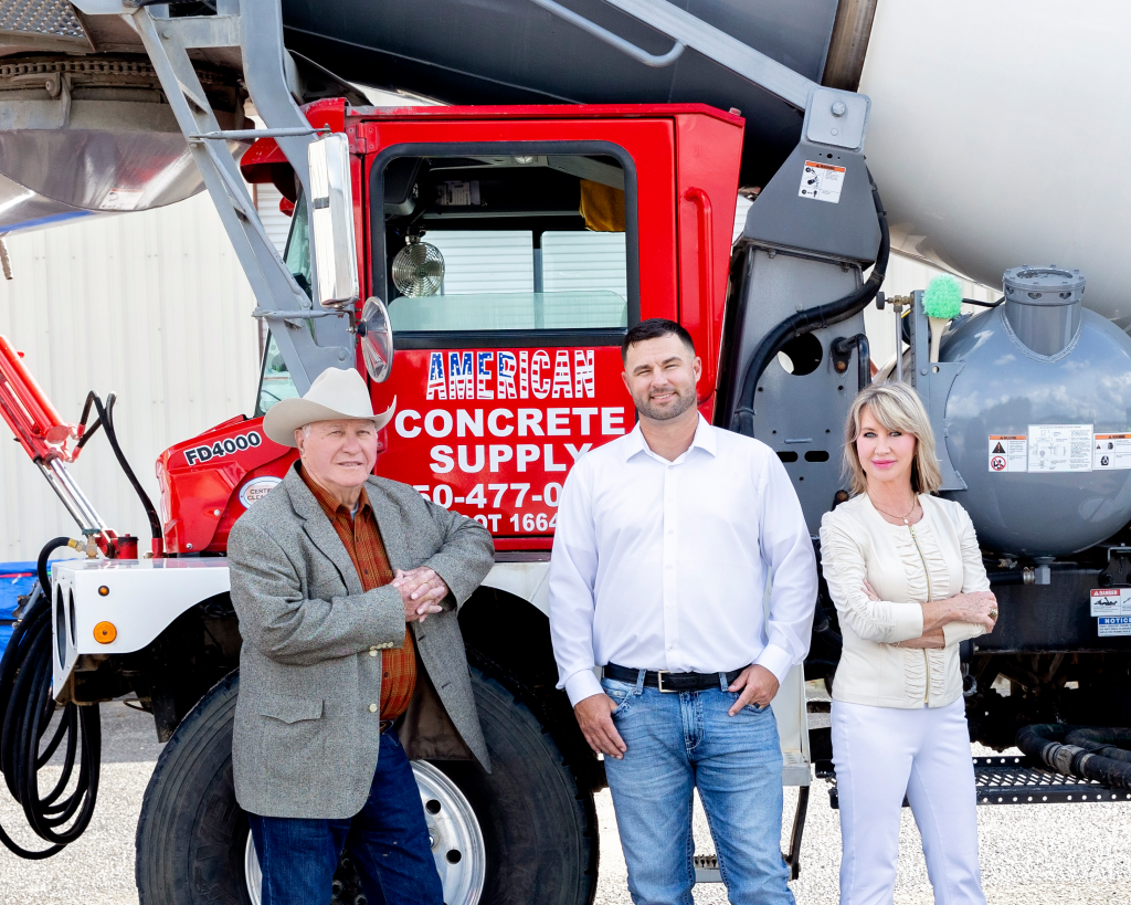 Three team members standing in front of an American Concrete Supply concrete mixer truck at their Pensacola plant and foundation